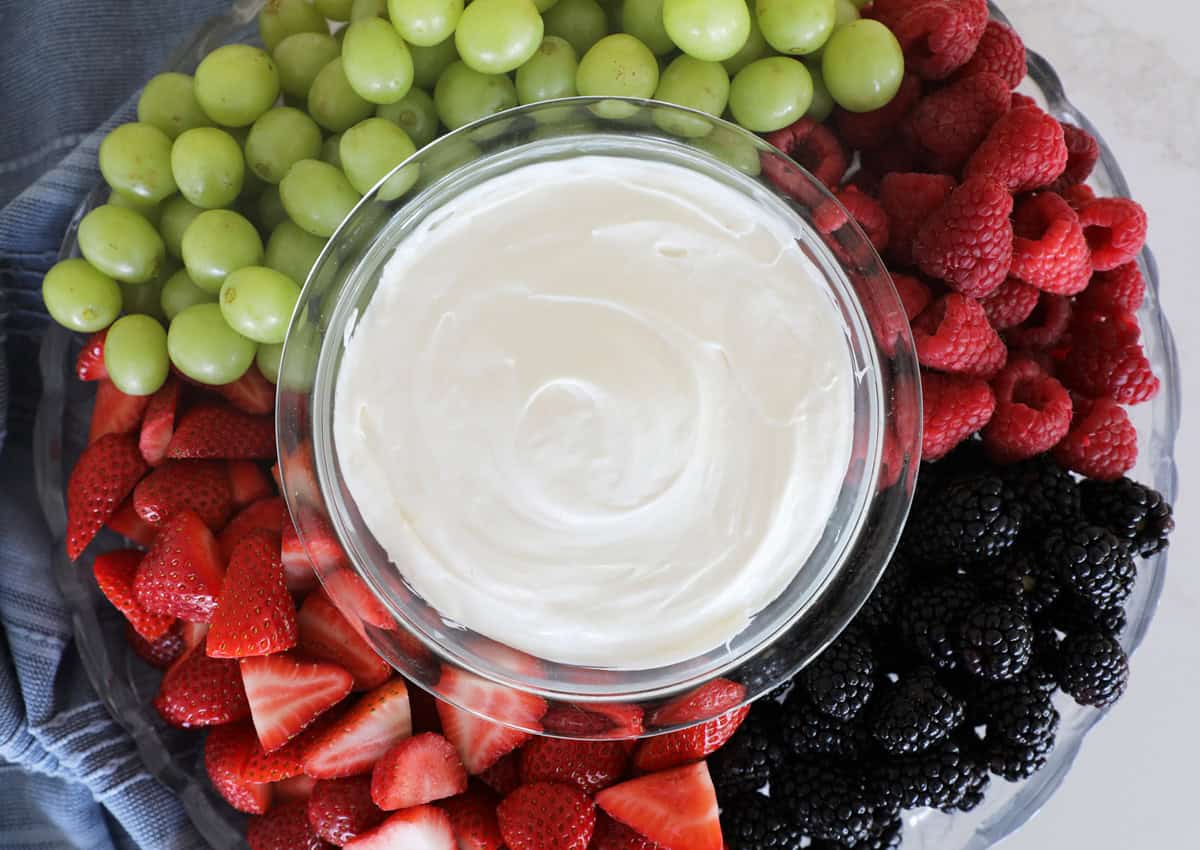A bird's eye view of a fruit tray with fruit dip in the center.