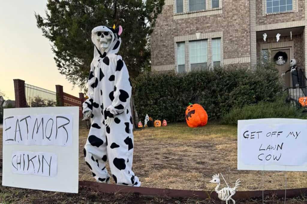 skeleton in a cow costume with a sign that says 'eat mor chikin'