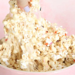 Marshmallow popcorn being pulled from a pink bowl, wiith gooey marshmallow caramel stretching.