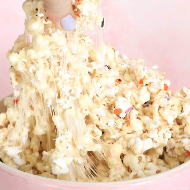 Marshmallow popcorn being pulled from a pink bowl, wiith gooey marshmallow caramel stretching.