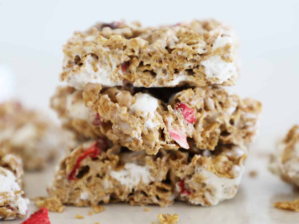 Three strawberry cereal bars stacked on top of each other against a white backdrop.